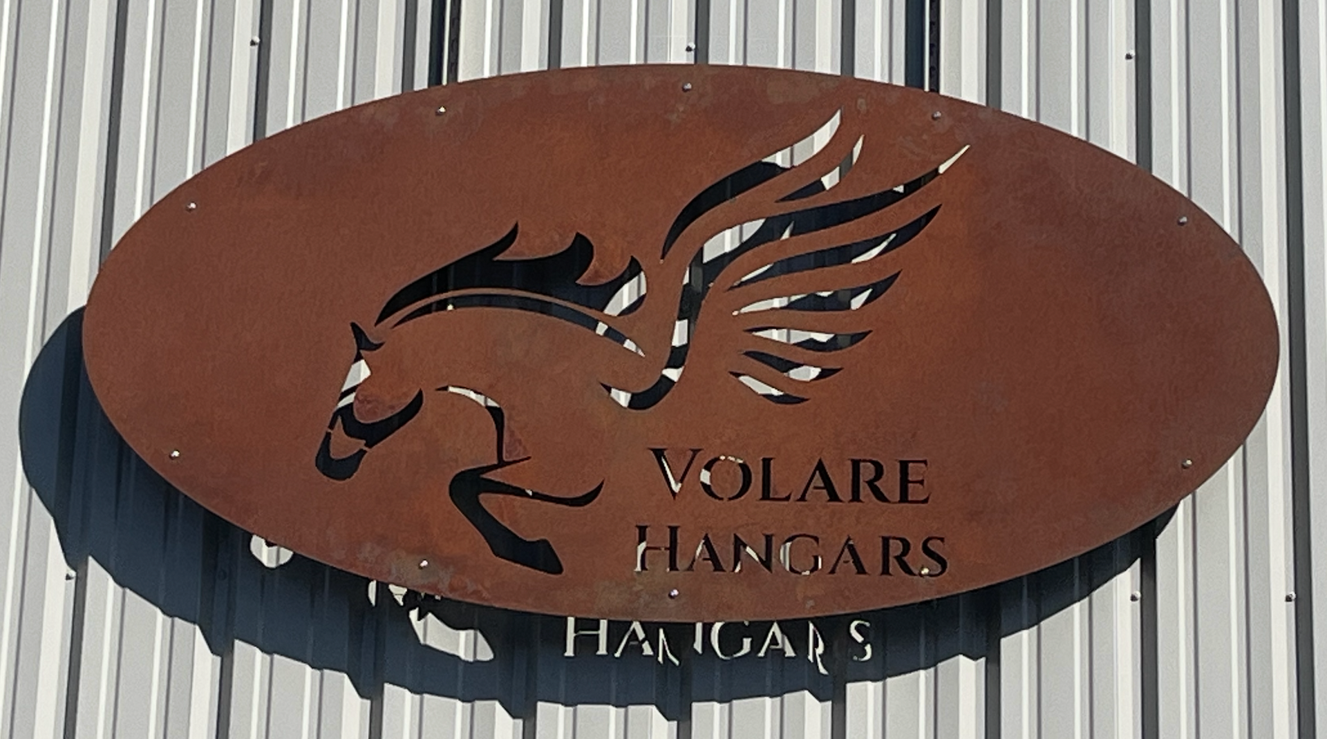 Volare Hangars pegasus oval sign mounted on metal siding